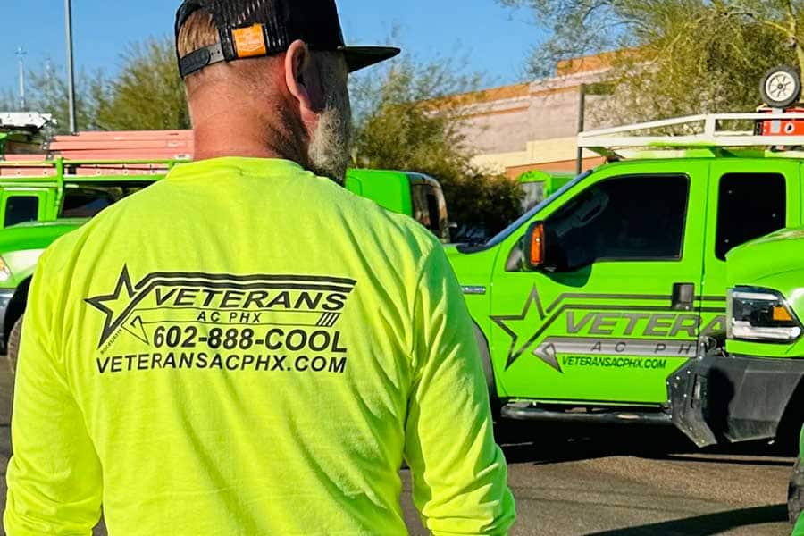 Veterans AC PHX employee in branded shirt standing near company trucks