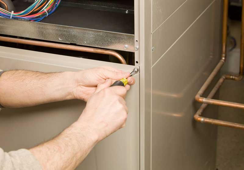 Technician using screwdriver to open a furnace panel