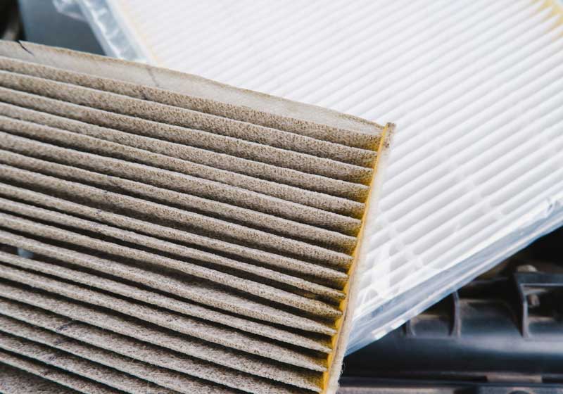 Close-up of a dirty air filter next to a clean one