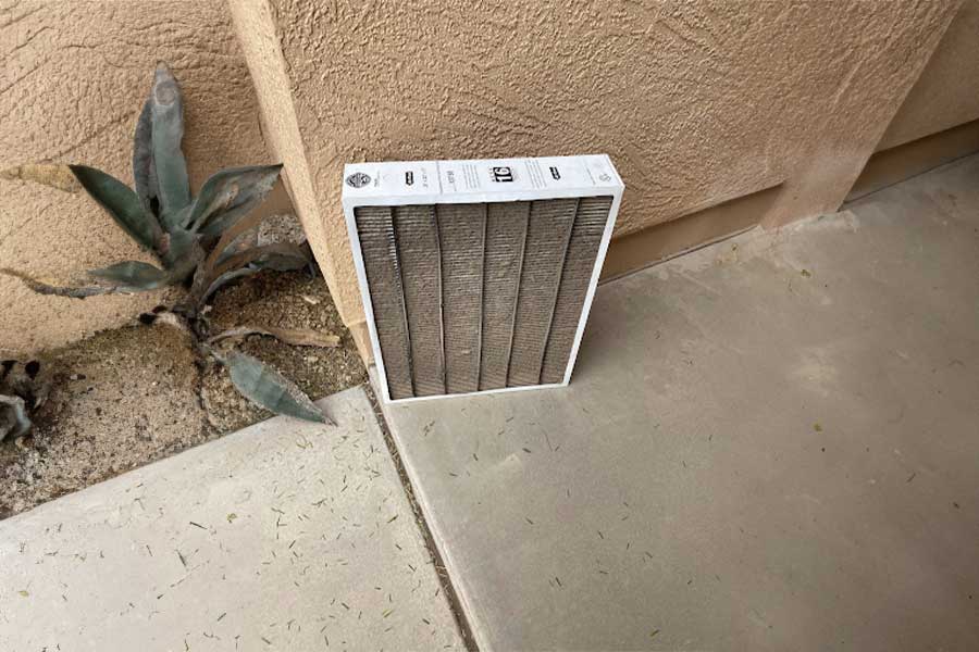 Used AC filter leaning against an exterior wall