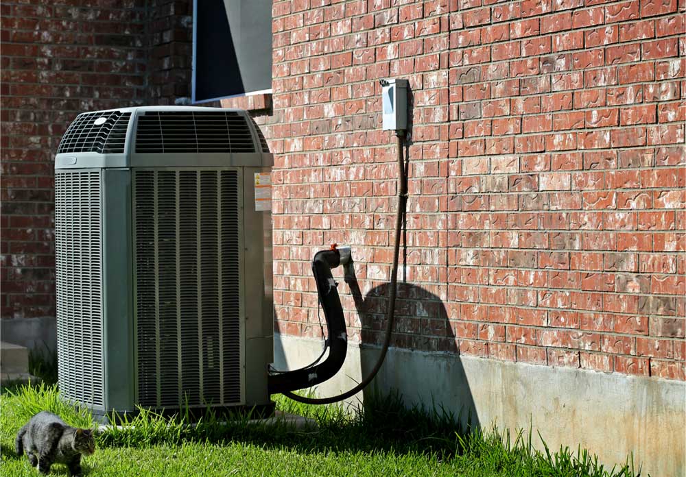 Outdoor AC unit installed next to a brick house