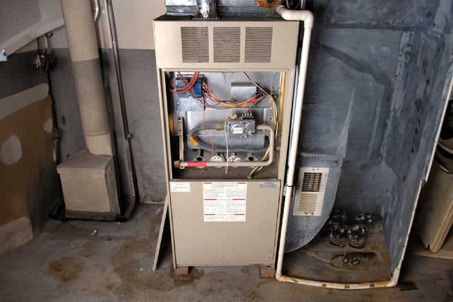 Old gas furnace with open panel showing internal wiring and components