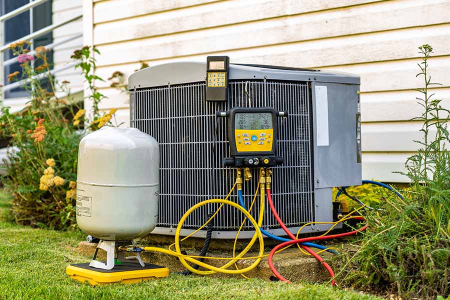 AC unit being serviced with gauges and refrigerant tank